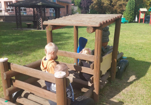 chłopcy siedzą w lokomotywie w ogrodzie