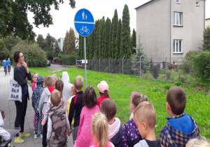 dzieci stoją na chodniku i oglądają znak informujący o ścieżce rowerowej