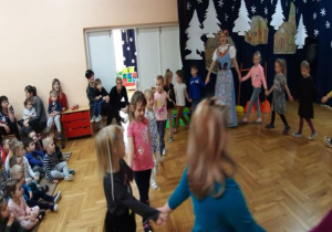tancerka tańczy w stroju śląskim z dziećmi w kole a pozostałe dzieci siedzą i oglądają