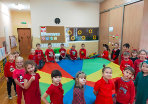 dzieci ubrane na czerwono pozują do zdjęcia z kolorową chustą animacyjną
