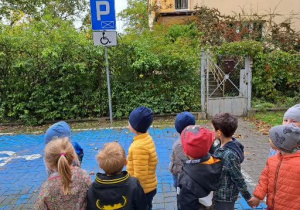 dzieci stoją przed znakiem i miejscem do parkowania dla niepełnosprawnych