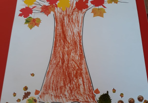 praca plastyczna - jesienne drzewo z liściami wyciętymi z kolorowego papieru a pod drzewem naklejone żołedzie, kasztany i liście