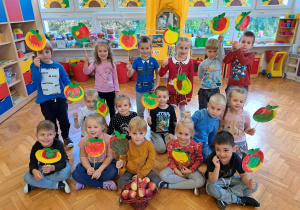 przedszkolaki z grupy VI z emblematami jabłek na patyku wykonanych z talerzy papierowych i pomalowanych farbą