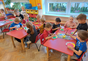 dzieci malują farbą plakatową talerzyki w kształcie jabłek