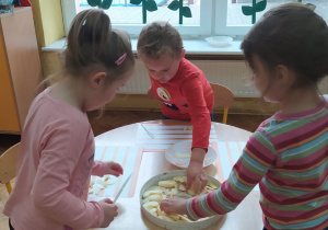 przedszkolaki układają pokrojone jabłka w plastry na sitkach suszarki do owoców