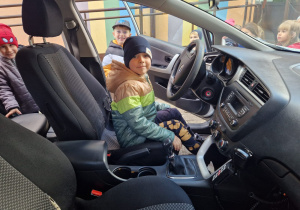 chłopiec siedzi na miejscu kierowcy w radiowozie