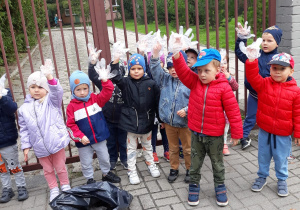 dzieci przed bramą przedszkola z założonymi na dłoniach rękawiczkami