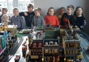dzieci ogladają miasteczko zbudowane z klocków Lego: kamienice, drogi i tory