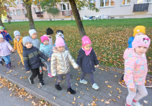 przedszkolaki poruszają się parami po chodniku