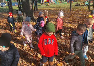na placu zabaw dzieci spacerują po kolorowych liściach