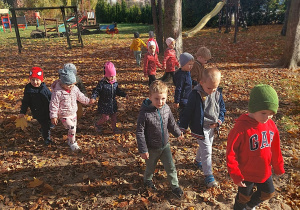 na placu zabaw dzieci spacerują po kolorowych liściach