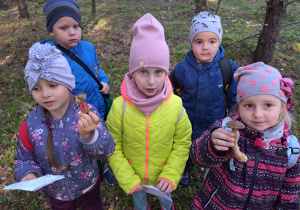 w lesie - dzieci pokazują znalezione grzyby jadalne