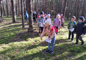 w lesie - przedszkolaki w trakcie rzucania szyszką na odległość