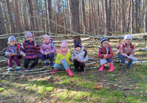 w lesie - dziewczynki siedzą na brzozowych gałązkach zwalonego drzewa