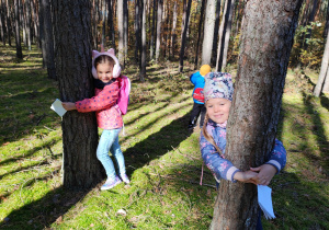 w lesie - dzieci przytulają się każdy do swojego drzewa