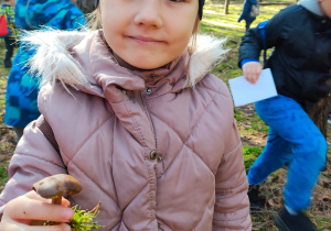 w lesie - dziewczynka pokazuje znalezionego grzybka