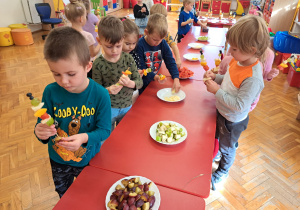 dzieci wybierają sobie owoce i nakłuwają je na szaszłykowe patyki