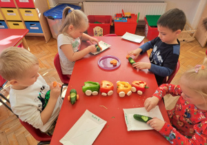 dzieci robią autko wyścigowe z zielonego ogórka, marchewki, małego pomidorka i wykałaczek