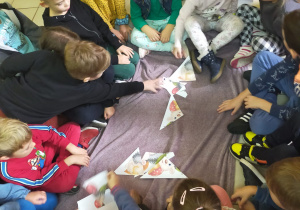 w bibliotece dzieci w grupie układają duże puzzle o jeżyku