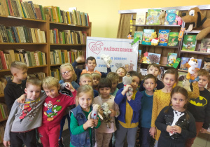w bibliotece dzieci z grupy III pozują do zdjęcia stojąc przed plakatem "Październik miesiącem opieki nad zwierzętami"