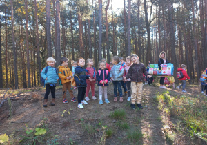 przedszkolaki z plecakami stoją na małej górce w lesie