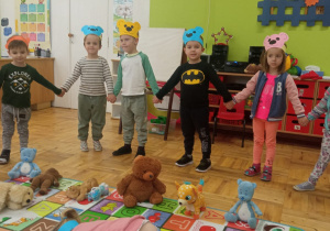 przedszkolaki bawią się w zabawę "Stary niedźwiedź" a maskotki misiów leżą w środku koła wraz z dziewczynką, która jest misiem