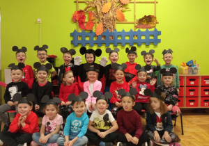 dzieci z grupy I pozują do zdjęcia grupowego w czarnych opaskach z uszami Myszki Miki