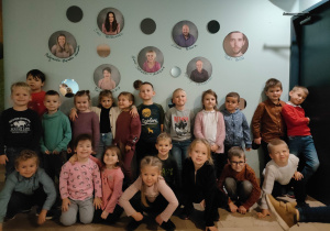 dzieci z grupy VIII pozują do zdjęcia grupowego na tle ściany z portretami aktorów powieszonymi na ścianie