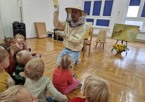 pszczelarz pokazuje dzieciom plaster wosku