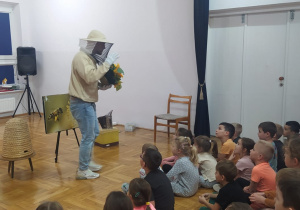 prtzedszkolaki słuchają wykładu pszczelarza, który trzyma słoneczniki