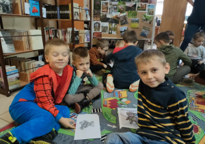 w bibliotece - chłopcy siedzą wokół ułożonych puzzli z misiem