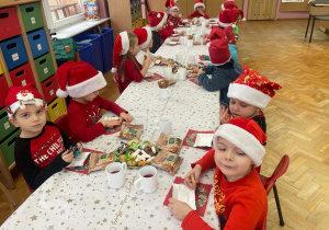 dzieci siedzą przy stolikach i jedzą słodycze