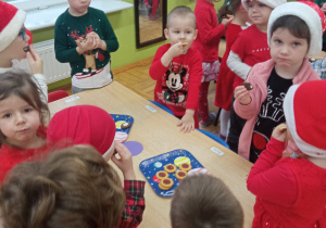 przedszkolaki jedzą słodkie cisteczka ustawione na stoliku