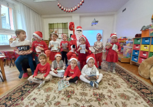 dzieci z grupy V w czerwonym ubraniach pozują do zdjęcia z Mikołajem