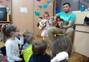 dziewczynka trzy ma ukulele a tata gra na gitarze