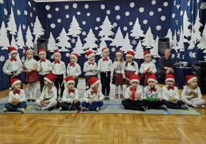 dzieci z grupy I w białych bluzkach i czerwonych czapkach pozują do zdjęcia grupowego