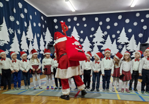 dzieci stoją w szeregu i witają się z Mikołajem