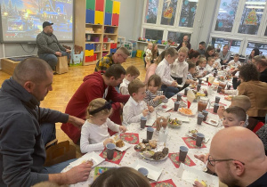 przedszkolaki z bliskimi siedzą przy świątecznie udekorowanych stołach i częstują się słodkościami