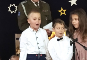 trójka przedszkolaków z naszego przedszkola śpiewają kolędę wraz wraz ze starszym sierżantem Marcinem Kowalczykiem z 15 Brygady Wsparcia Dowodzenia w Sieradzu