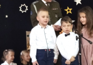 troje przedszkolaków śpiewa kolędę wraz ze starszym sierżantem Marcinem Kowalczykiem z 15 Brygady Wsparcia Dowodzenia w Sieradzu