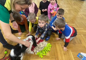 przedszkolaki chowją przysmaki dla psa w jego zabawce