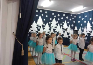 przedszkolaki stoją ustawione w parach chłopiec z dziewczynką podczas występu dla babci i dziadka
