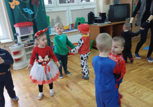 dzieci tańczą w parachw kostiumach karnawałowych