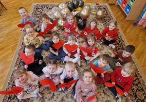zdjęcie grupowe dzieci z grupy V z "walentynkami" - wachlarzami w kształcie czerwonych serc różnej wielkości