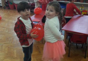 taniec w parach z balonem w kształcie serca umieszczonym między brzuchami dzieci
