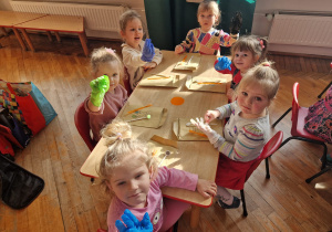 dziewczynki siedząc przy stoliku pokazują założone jednorazowe rękawiczki