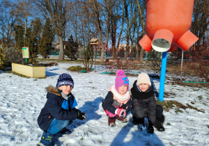 w ogrodzie zimowym - dzieci lepią kulki śniegowe kucając pod koszem do piłki