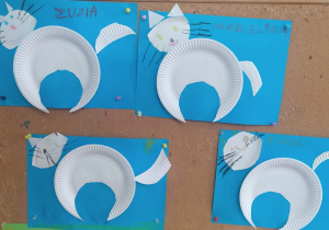 prace plastyczne - białe koty z papierowego talerzyka na niebieskich kartkach