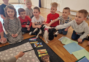 przedszkolaki słuchają opiekunki i głaszczą psa