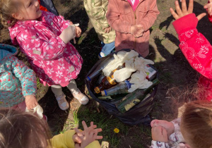 przedszkolaki wyrzucają rękawiczki jednorazowe do worka ze śmieciami